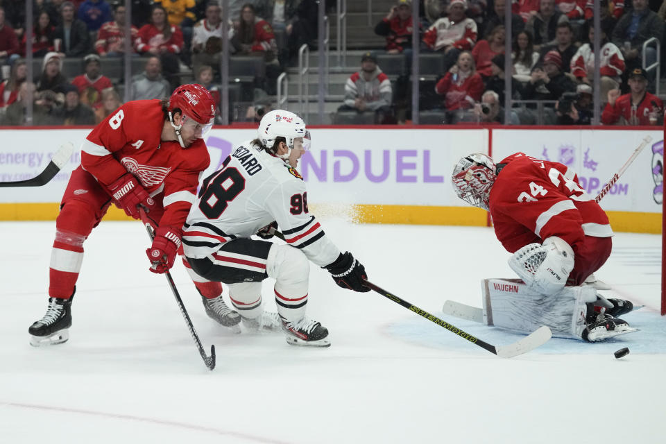 Detroit Red Wings goaltender Alex Lyon (34) stops a Chicago Blackhawks center Connor Bedard (98) shot as Ben Chiarot (8) defends in the third period of an NHL hockey game Thursday, Nov. 30, 2023, in Detroit. (AP Photo/Paul Sancya)