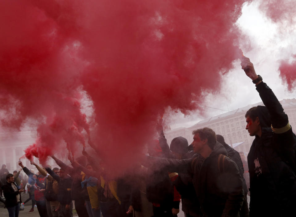 Protesters light flares during a rally in Independence Square in Kyiv, Ukraine, Sunday, Oct. 6, 2019. Thousands are rallying in the Ukrainian capital against the president's plan to hold a local election in the country's rebel-held east, a move seen by some as a concession to Russia. (AP Photo/Efrem Lukatsky)