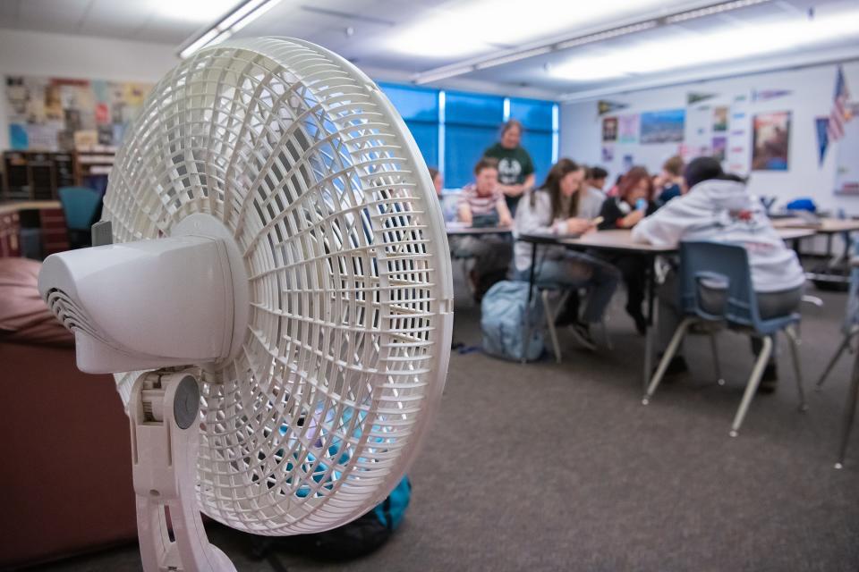 Fort Collins High School students feel a breeze from a standing fan during an afternoon journalism class Tuesday in Fort Collins. Because the school does not have a working air conditioning system, the second-floor classroom uses four portable fans to circulate air on hot days.