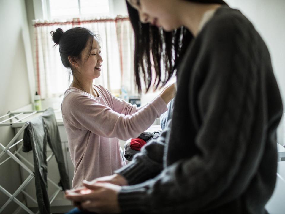 mother and teen daughter at home doing laundry