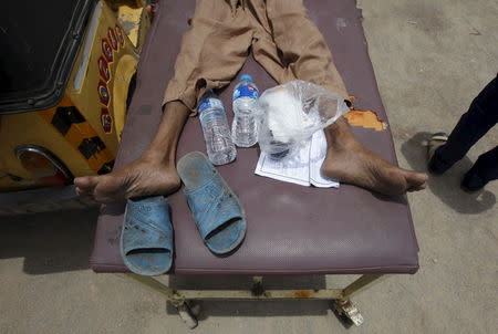 A man, who collapsed due to the heat, lies on a stretcher with his belongings of sandals and water bottles, outside Jinnah Postgraduate Medical Centre (JPMC) in Karachi, Pakistan, June 24, 2015. REUTERS/Akhtar Soomro