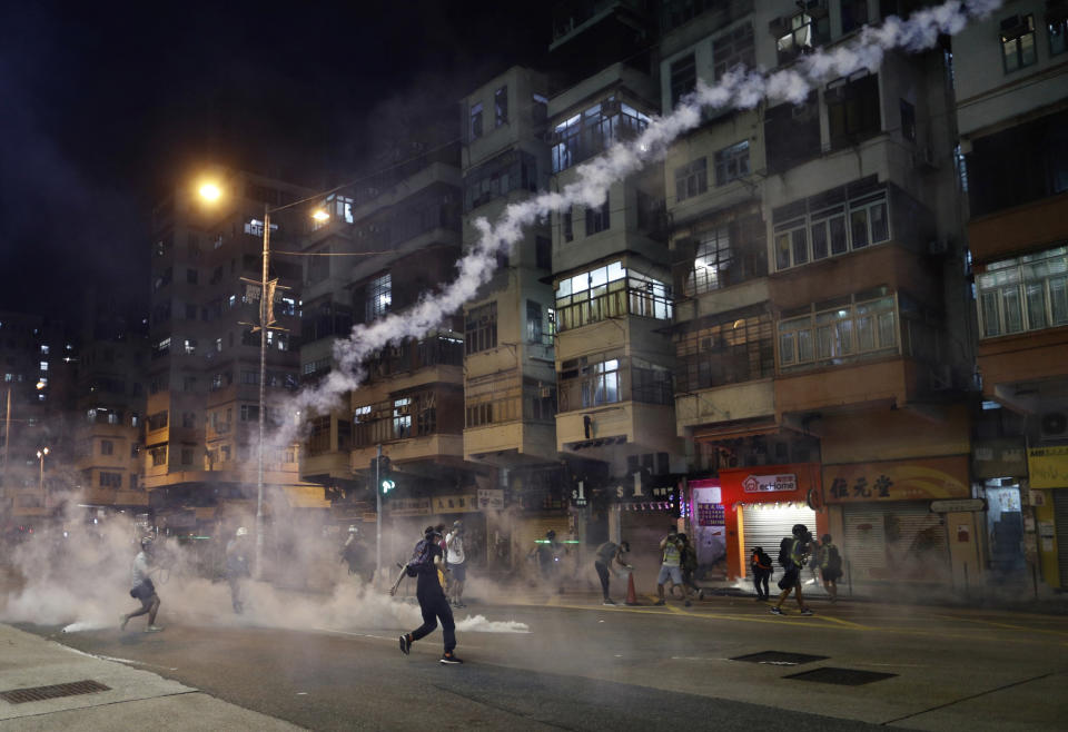 Protesters react to tear gas from Shum Shui Po police station in Hong Kong on Wednesday, Aug. 14, 2019. German Chancellor Angela Merkel is calling for a peaceful solution to the unrest in Hong Kong amid fears China could use force to quell pro-democracy protests.(AP Photo/Vincent Yu)