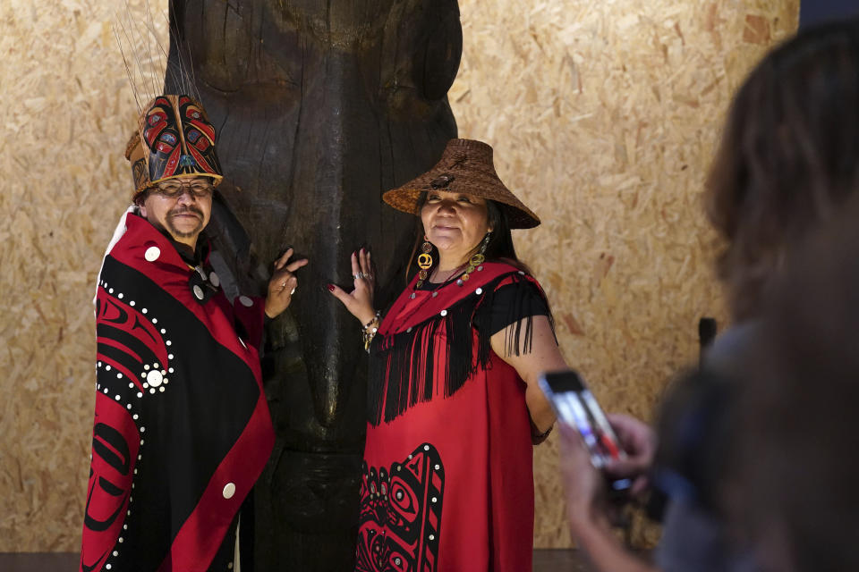Earl Stephens, who has the Nisga'a cultural name Chief Ni'is Joohl, left, and Pamela Brown from the Nisga'a nation pose beside the 11-metre tall memorial pole, during a visit to the National Museum of Scotland, ahead of its return to what is now British Columbia, in Edinburgh, Monday, Aug. 28, 2023. Members of a Canadian First Nation held a spiritual ceremony on Monday at a Scottish museum to begin the homeward journey of a totem pole stolen almost a century ago. (Andrew Milligan/PA via AP)