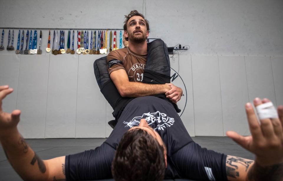 Zach Mabey, 31, a brown belt in Brazilian jujitsu (BJJ), grapples with one of his students, Martin Chochkeh, during a training session inside the 313 Brazilian Jiu Jitsu gym in Detroit on Wednesday, Aug. 16, 2023.