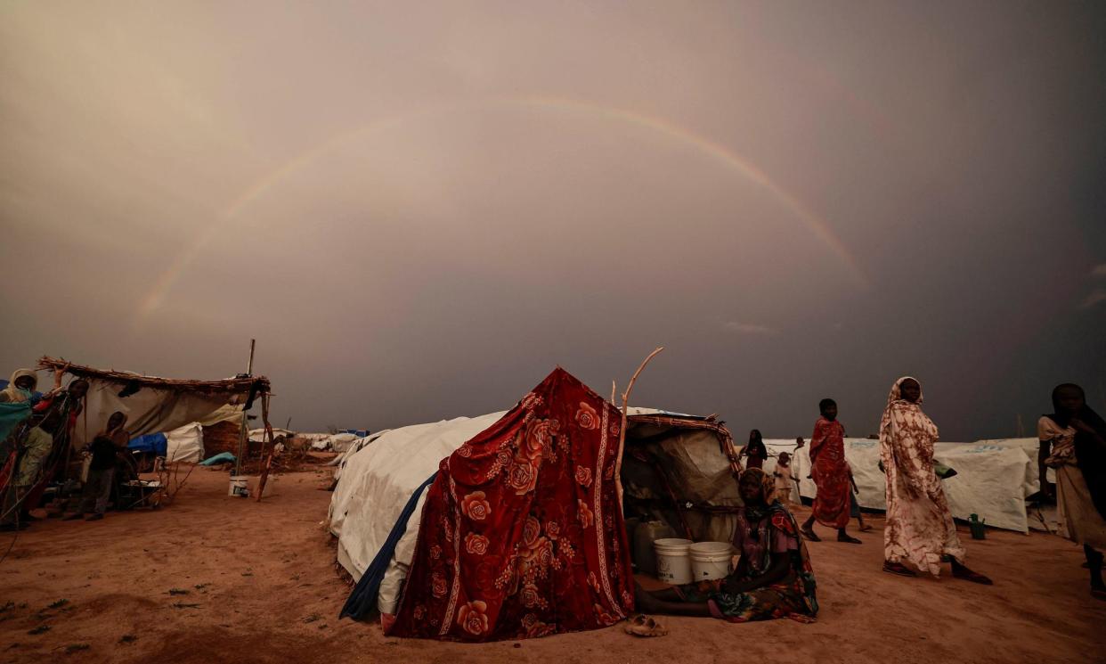 <span>A rainbow is seen over the makeshift shelters of Sudanese people who fled the conflict in Geneina, during sunset in Adré, Chad last July.</span><span>Photograph: Zohra Bensemra/Reuters</span>