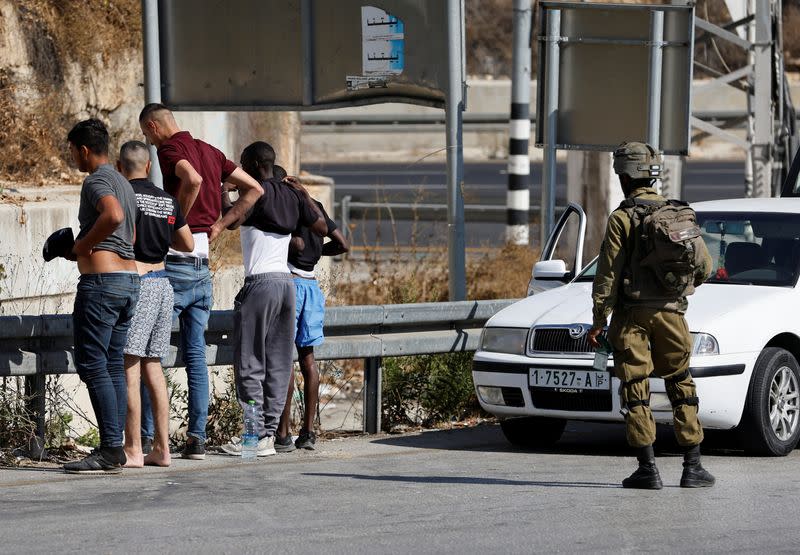 An Israeli soldier checks Palestinians at a checkpoint in Hebron