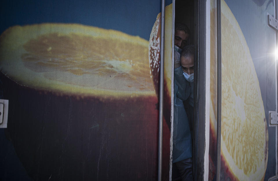 Palestinian medics inside a truck prepare to unload 20,000 doses of Russian-made Sputnik V vaccine upon its arrival to Gaza Strip, at the Rafah crossing border with Egypt, Sunday, Feb. 21, 2021. The 20,000 doses of Russia's Sputnik V, donated by the United Arab Emirates and organized by Abbas rival Mohammed Dahlan, entered the Palestinian enclave through its border with Egypt. (AP Photo/Khalil Hamra)