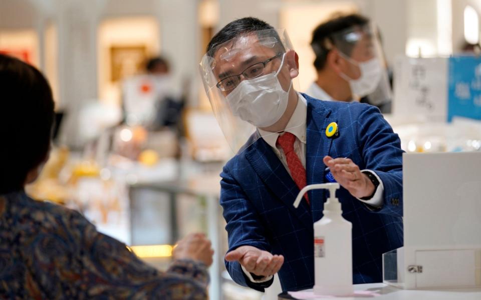  A Matsuya Ginza staff member wearing protective gear invites a customer to use hydroalcoholic solution during the reopening of the department store's food retailing floor after a month and a half of closure -  FRANCK ROBICHON/EPA-EFE/Shutterstock/Shutterstock
