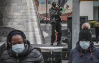 FILE - In this April 18, 2020 file photo Harlem resident who goes by the name New World Warrior, center, plays "Lift Every Voice And Sing" on his trumpet at one of multiple stops along 125th Street, blaring the song repeatedly as people walk on by, in New York. The Black national anthem was born more than a century ago, but the popular hymn within the African American community called "Lift Every Voice and Sing" has been resurrected as a beacon of hope for all races during nationwide protests. (AP Photo/Bebeto Matthews, File)