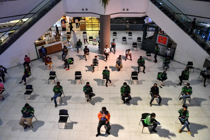 Staff of food delivery companies sit on social distancing chairs due to coronavirus disease (COVID-19) outbreak, as they wait for their costumers' orders at a department store in Bangkok