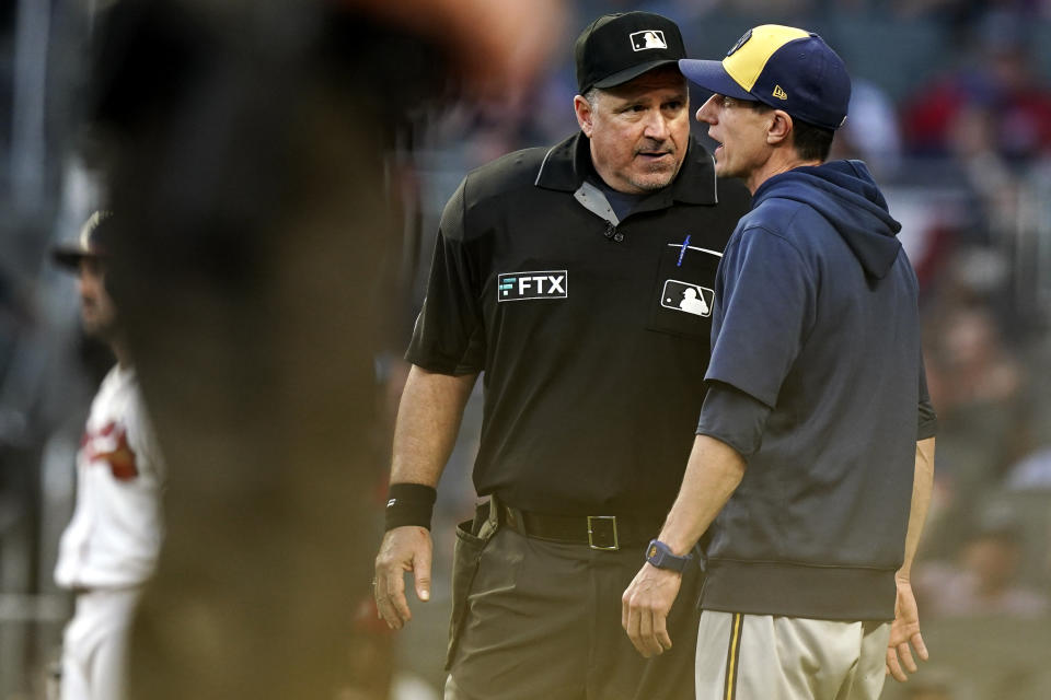 The umpire speaks to Milwaukee Brewers manager Craig Counsell during the fourth inning of Game 4 of a baseball National League Division Series against the Atlanta Braves, Tuesday, Oct. 12, 2021, in Atlanta. (AP Photo/Brynn Anderson)