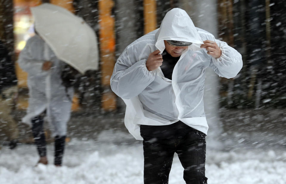 People attempt to shield themselves as it snows in Tokyo, Monday, Jan. 14, 2013. (AP Photo/Koji Sasahara)