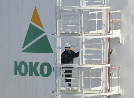 FILE PHOTO: A worker climbs up the stairs of oil container at a pumping station near Priobskoye oil field in Siberia