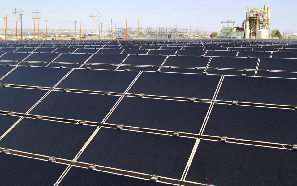 FILE - In April 20, 2011, file photo, rows of solar panels that make up Public Service Company of New Mexico's new 2-megawatt photovoltaic array sit in front of the utility's natural gas-fired generating station in Albuquerque, N.M. The parent company of New Mexico’s largest electric utility will become part of energy giant Iberdrola’s global holdings under a multibillion-dollar merger. Under the agreement announced Wednesday, Oct. 21, 2020, Iberdrola's majority-owned U.S. subsidiary Avangrid will acquire PNM Resources and its assets in New Mexico and Texas. The merger will require approval from a number of state and federal regulators in a process that's expected to take the next 12 months. (AP Photo/Susan Montoya Bryan, File)