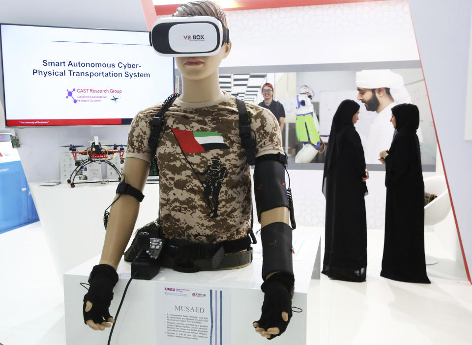 Emirati women speak to each other at an exhibit by the United Arab Emirates University at the International Defense Exhibition and Conference in Abu Dhabi, United Arab Emirates, Sunday, Feb. 17, 2019. The biennial arms show in Abu Dhabi comes as the United Arab Emirates faces increasing criticism for its role in the yearlong war in Yemen. (AP Photo/Jon Gambrell)