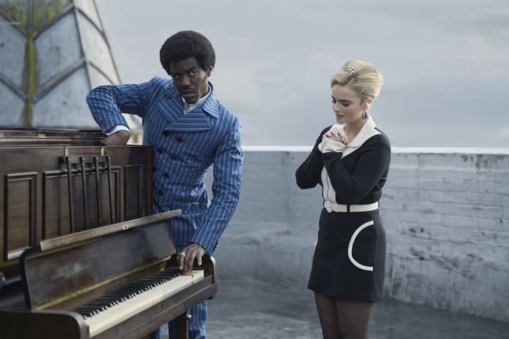 The Doctor and Ruby stand near a piano in Doctor Who.
