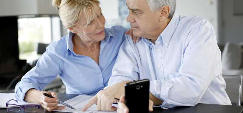 An elderly couple has a discussion over paperwork.