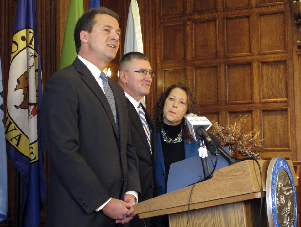 FILE - This Feb. 7, 2014 file photo shows Montana Gov. Steve Bullock, left, introducing his Lt. Gov. John Walsh, as the appointee to the Senate in Helena, Mont. Walsh, standing beside his wife Janet Walsh, replaced U.S. Sen. Max Baucus and is running to keep the seat against Republican U.S. Rep. Steve Daines. Max Baucus’ decision not to seek re-election to the Senate after 35 years opened the door for Republicans to pick up one of the six Democratic seats they need to recapture control of the Senate. But his early resignation after being named U.S. ambassador to China may have bolstered Democratic prospects of retaining the seat they have held for a century, thanks to the value of incumbency. (AP Photo/Matt Volz, File)