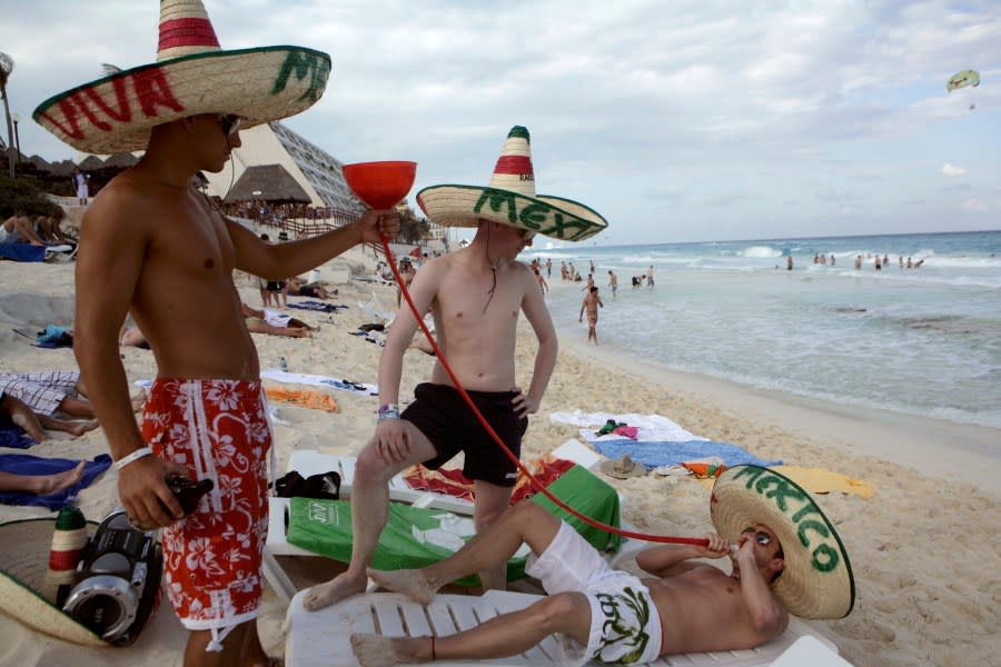 Spring breakers drink at the beach in the resort city of Cancun, Mexico, Thursday, March 12, 2009. (AP Photo/Israel Leal)