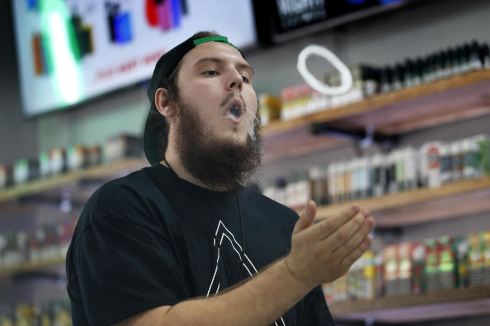 In this Tuesday, Sept. 3, 2019, photo, Devin Lambert, the manager at Good Guys Vape Shop, demonstrates to blow a vapor ring while using an e-cigarette in Biddeford, Maine. Efforts to ban flavored e-cigarettes and reduce their appeal to youngsters have sputtered under industry pressure in over a half-dozen states this year. The industry and its lobbyists urged lawmakers to leave mint and menthol alone. A proposed ban that President Donald Trump outlined Wednesday, Sept. 11, would supersede any state inaction and includes a ban on mint and menthol. (AP Photo/Robert F. Bukaty)