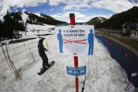FILE - In this Wednesday, May 27, 2020, file photo, a sign reminds skiers and snowboarders to practice social distancing while wearing a face covering in lift lines at the reopening of Arapahoe Basin Ski Resort, which closed in mid-March to help in the effort to stop the spread of the new coronavirus, in Keystone, Colo. The virus will create a new environment for skiers and snowboarders in the winter sports season ahead. (AP Photo/David Zalubowski, File)