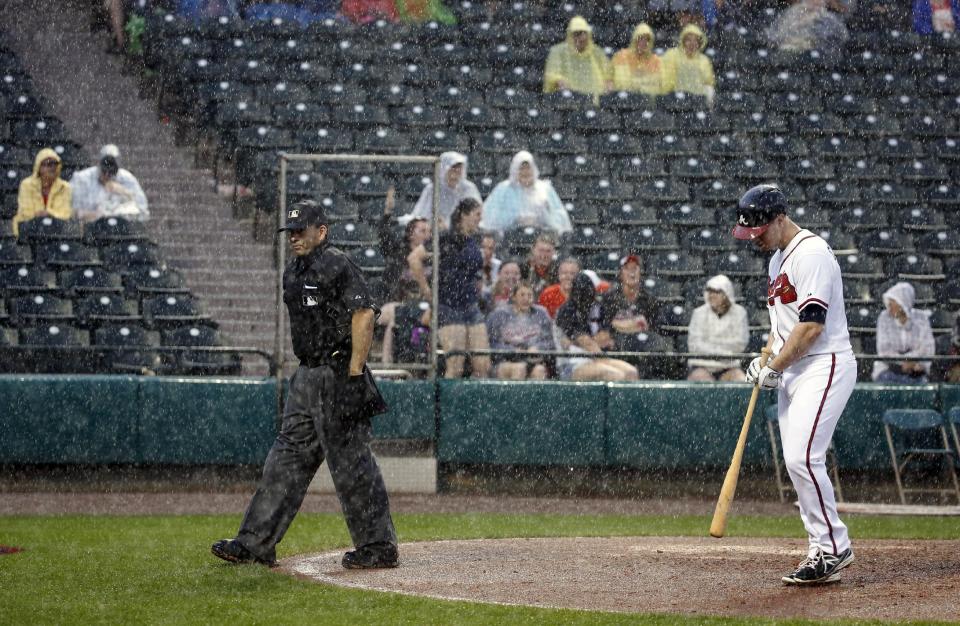 Home plate umpire Angel Campos, left, walks off the field after stopping the game with Atlanta Braves batter Todd Cunningham nearby in the ninth inning of a spring exhibition baseball game against the Detroit Tigers, Wednesday, Feb. 26, 2014, in Kissimmee, Fla. The Tigers won 6-5. The game was stopped because of rain with two outs in the bottom of the ninth and the Tigers were awarded the win. (AP Photo/Alex Brandon)