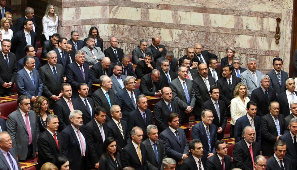 Members of parliament from the extreme right-wing Golden Dawn party, center background, remain seated as Greek Muslim lawmakers take the oath, not seen, during the swearing in ceremony at the Greek parliament in Athens, Thursday, May 17, 2012. Among the deputies to take their seats for a day are 21 from the Golden Dawn party, which rejects the neo-Nazi label. It campaigned on pledges to rid Greece of immigrants and clean up neighborhoods. (AP Photo/Thanassis Stavrakis)