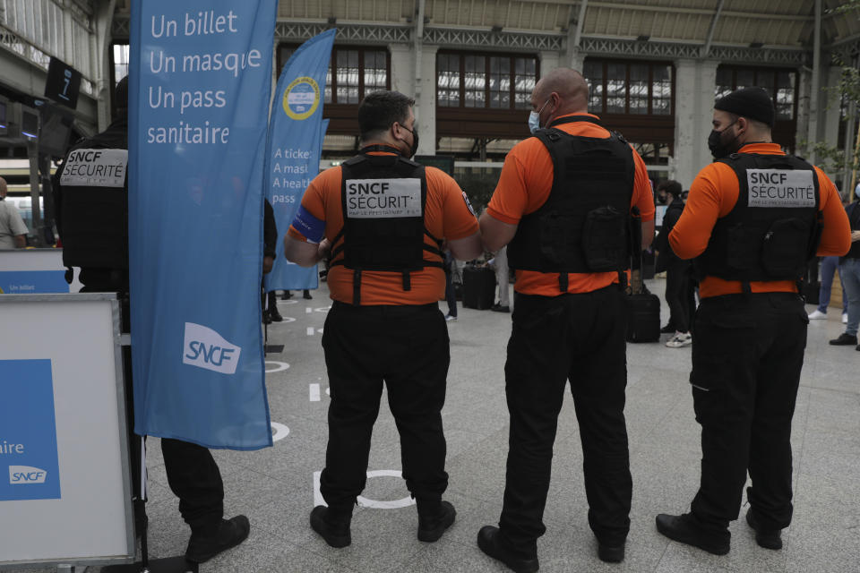 Security officers stand at the Gare de Lyon train station in Paris Monday Aug.9, 2021. Starting today, the pass will be required in France to access cafes, restaurants, long-distance travel and, in some cases, hospitals. It was already in place for cultural and recreational venues, including cinemas, concert halls, sports arenas and theme parks with a capacity for more than 50 people. (AP Photo/Adrienne Surprenant)