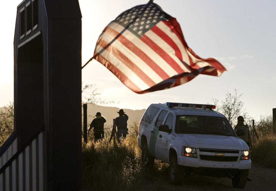 FILE - In this Dec. 15, 2010, file photo, an American flag on a nearby resident's home waves in the breeze near a U.S. Border Patrol truck blocking the road leading to a search area near where Border Patrol Agent Brian Terry was killed northwest of Nogales, Ariz. A man extradited to the U.S. from Mexico has pleaded not guilty to charges of pulling the trigger in Terry's slaying. Court records show Heraclio Osorio-Arellanes entered his plea during a Wednesday, Aug. 1, 2018, arraignment in U.S. District Court in Tucson. (Greg Bryan/Arizona Daily Star via AP, File)