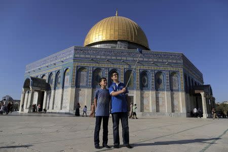 Palestinian Muhamad Younis (R), 14, from the West Bank city of Ramallah, takes a selfie photo with his brother in front of the Dome of the Rock on the compound known to Muslims as the Noble Sanctuary and to Jews as Temple Mount, in Jerusalem's Old City, during the holy month of Ramadan, June 29, 2015. REUTERS/Ammar Awad