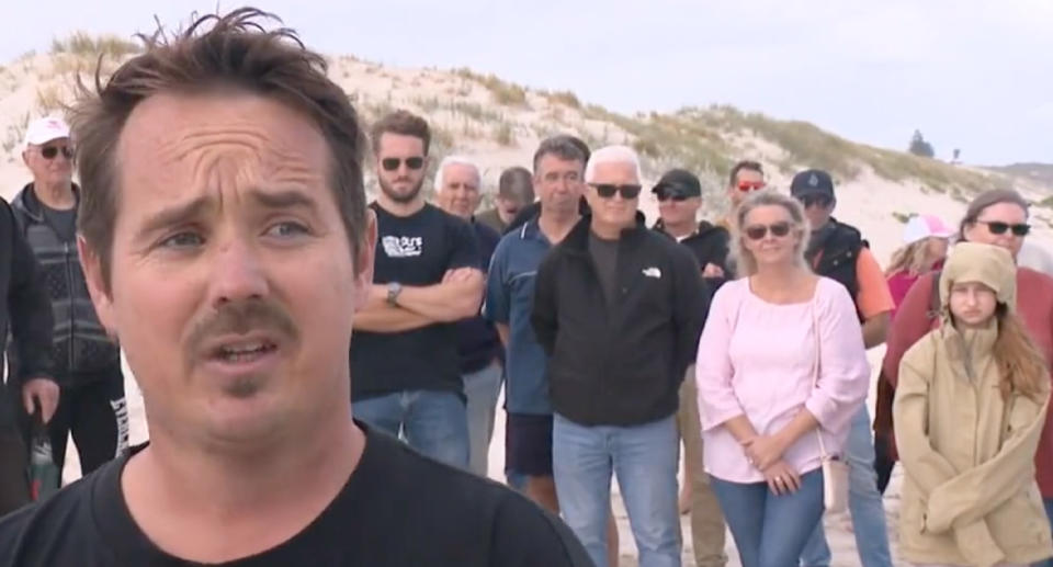 Ben Allen can be seen standing in front of a group of unhappy residents on the beach.