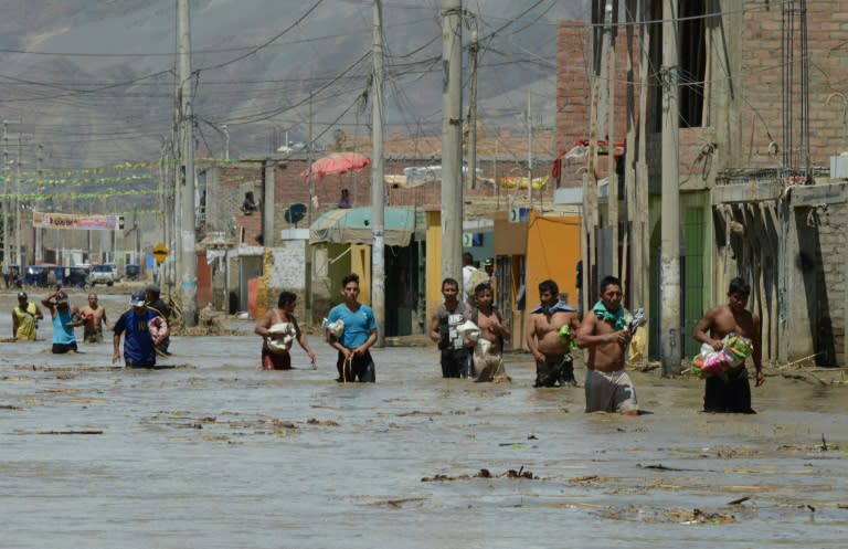 Residents of the town of Huarmey, 300 km north of Lima, wade through muddy water in the street after a flash flood hit the area the night before