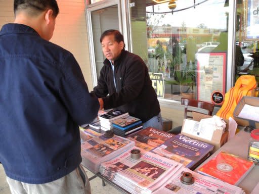 Newspaper vendor Tony Nguyen serves a customer at a table full of Vietnamese-language publications about the US election at the Eden Center shopping complex in the Washington suburb of Falls Church, Virginia, on October 28, 2012. The campaigns of both President Barack Obama and Republican Mitt Romney have been reaching out to Asian Americans, who form the fastest growing US racial group