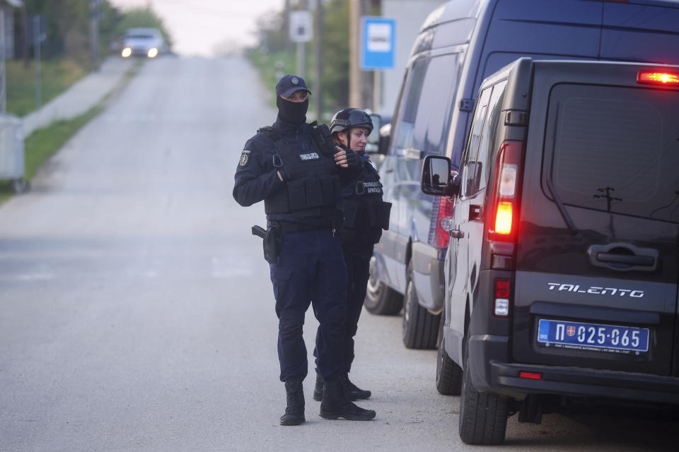 Police officers stand guard on a road in the village of Dubona, some 50 kilometers (30 miles) south of Belgrade, Serbia, Friday, May 5, 2023, as they block the road near the scene of a Thursday night attack. A shooter killed multiple people and wounded more in a drive-by attack late Thursday in Serbia's second such mass killing in two days, state television reported. (AP Photo/Armin Durgut)