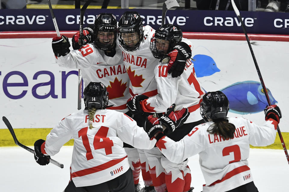 Canada forward Marie-Philip Poulin, top left, celebrates with defensewoman Renata Fast (14), forward Brianne Jenner (19), forward Sarah Fillier (10) and defensewoman Jocelyne Larocque after scoring against the United States during the third period in the final at the IIHF Women's World Hockey Championships in Utica, N.Y., Sunday, April 14, 2024. (AP Photo/Adrian Kraus)