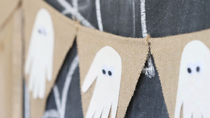 handprint cutouts decorated with googly eyes to look like ghosts glued to burlap pennants for halloween banner