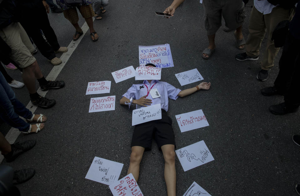 A High school student lies on the ground with placards around him during a protest rally in Bangkok, Thailand, Saturday, Sept. 5, 2020. The student's demonstration comes at a time of mass anti-government protests led predominantly by university students, putting added strain on the under-pressure administration of Prime Minister Prayuth Chan-ocha. Placard on his cafe reads as "Education kills me" (AP Photo/Gemunu Amarasinghe)