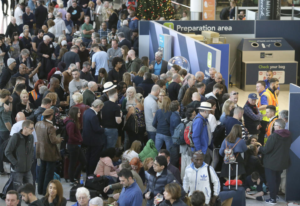 People wait near the departures gate at Gatwick airport, near London, as the airport remains closed with incoming flights delayed or diverted to other airports, after drones were spotted over the airfield last night and this morning, Thursday, Dec. 20, 2018. London's Gatwick Airport remained shut during the busy holiday period Thursday while police and airport officials investigate reports that drones were flying in the area of the airfield. (AP Photo/Tim Ireland)