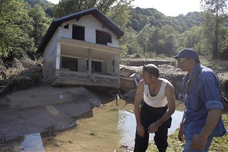 Two men stand near a house tilted by floods in the town of Valjevo, southwest from Belgrade May 21, 2014. Picture taken May 21. REUTERS/Marko Djurica