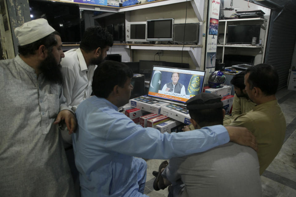 People watches news channels broadcast a live address to the nation by Pakistan's Prime Minister Imran Khan at a market, in Peshawar, Pakistan, Thursday, March 31, 2022. Pakistan's embattled Prime Minister Khan remained defiant on Thursday, telling the nation that he will not resign even as he faces a no-confidence vote in parliament and the country's opposition says it has the numbers to push him out. (AP Photo/Muhammad Sajjad)