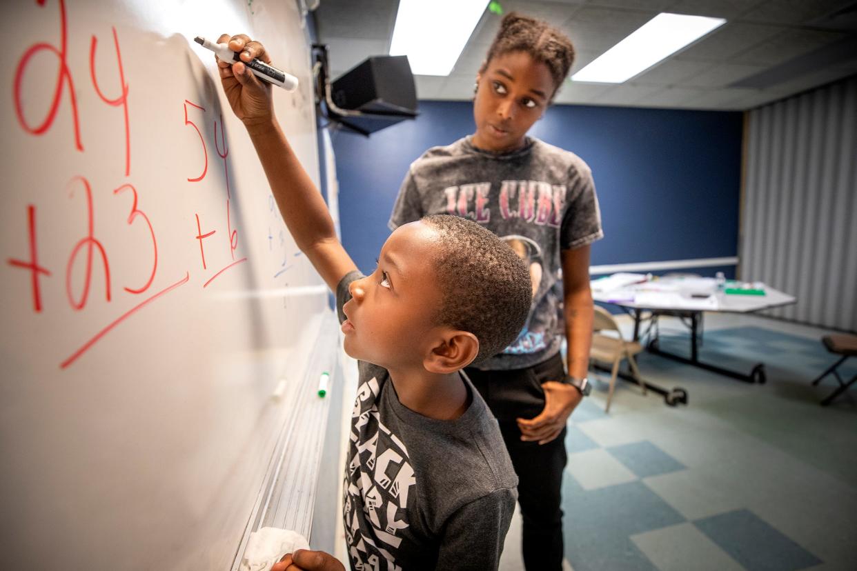 Shelby Reeves helps Willie Evans, 7, with some math problems at the B Street Community Service Center in Lake Wales Fl. Wednesday June 15,  2022. The Green & Gold Foundation hosts summer interns from Polk high schools and out of school ages 16-24 to teach kids in Lake Wales who are behind in school.ERNST PETERS/ THE LEDGER