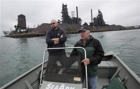 Robert Burns (R) , a member of the environmental group 'Friends of the Detroit River', drives his boat along the Detroit River past Zug Island, along with Nicholas Schroeck, executive Director of Great Lakes Environmental Law Center, during an interview about The City of Detroit Water and Sewerage Wastewater Treatment Plant in Detroit, Michigan October 1, 2013. REUTERS/Rebecca Cook