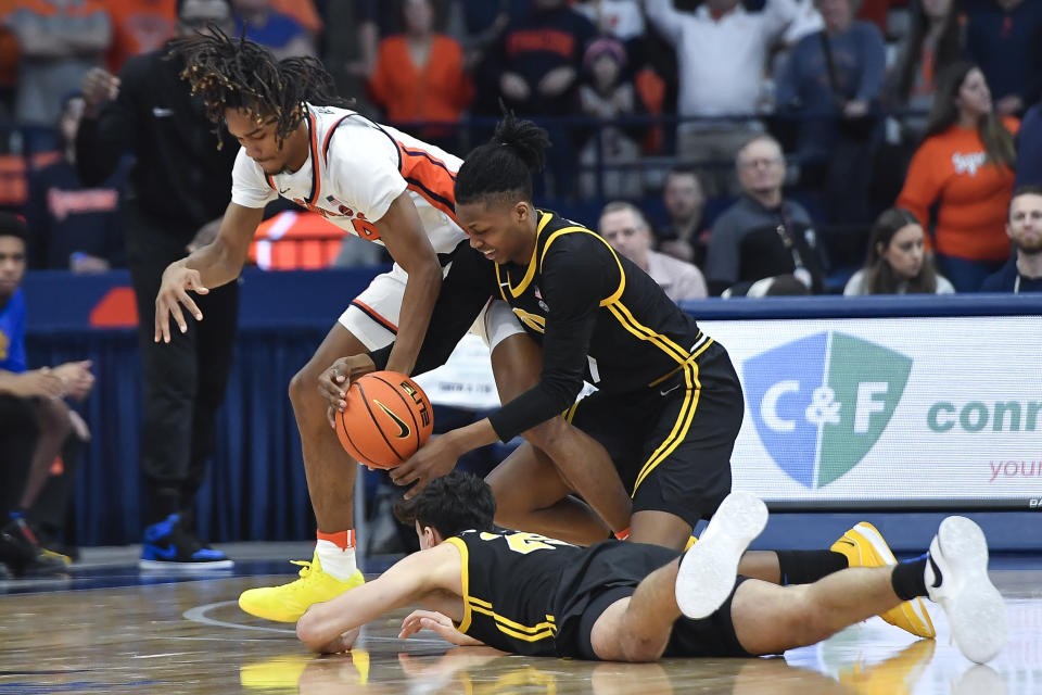 Syracuse forward Chris Bell, left, reaches for a loose ball against Pittsburgh guard Carlton Carrington, right, and forward Guillermo Diaz Graham during the second half of an NCAA college basketball game in Syracuse, N.Y., Saturday, Dec. 30, 2023. (AP Photo/Adrian Kraus)