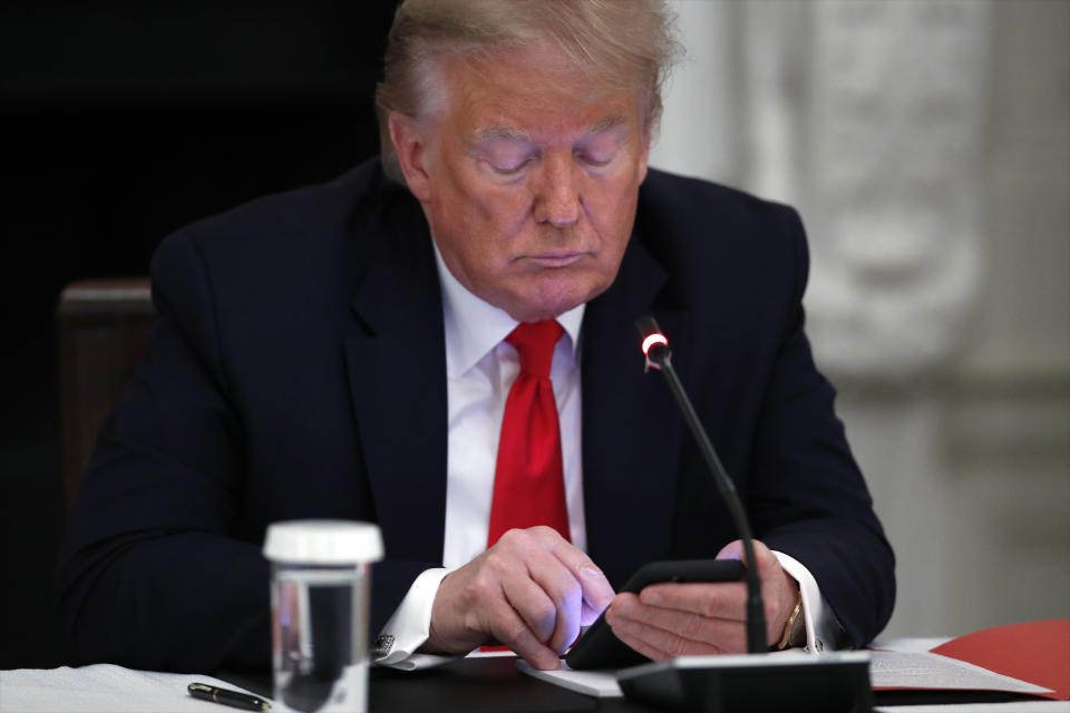 El presidente Donald Trump mira su teléfono durante un evento en la Casa Blanca.  (AP Photo/Alex Brandon)