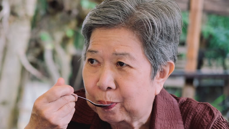 Senior woman eating with a spoon
