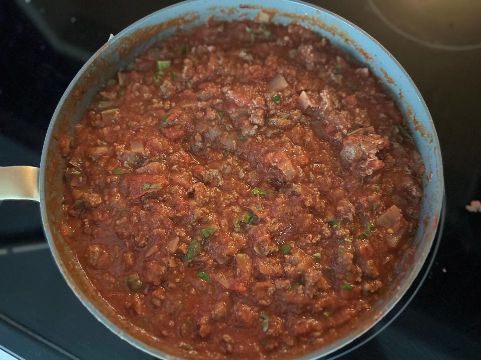 sauce made from meat, tomatoes, and seasoning simmering in a pot on the stove