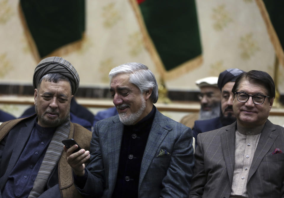 Afghan presidential candidate Abdullah Abdullah looks at his phone during a press conference in Kabul, Afghanistan, Sunday, Dec. 22, 2019. Afghanistan's election commission said the country's incumbent, President Ashraf Ghani, has won a second term in office, according to a preliminary vote count. But his opponents can still challenge the results that were announced on Sunday. (AP Photo/Rahmat Gul)
