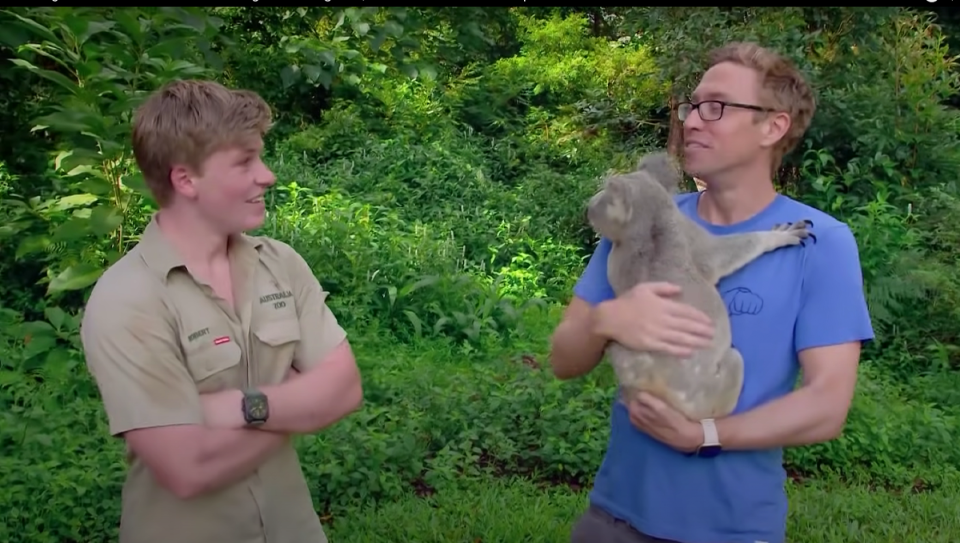 Robert Irwin and comedian Russell Howard holding a koala.