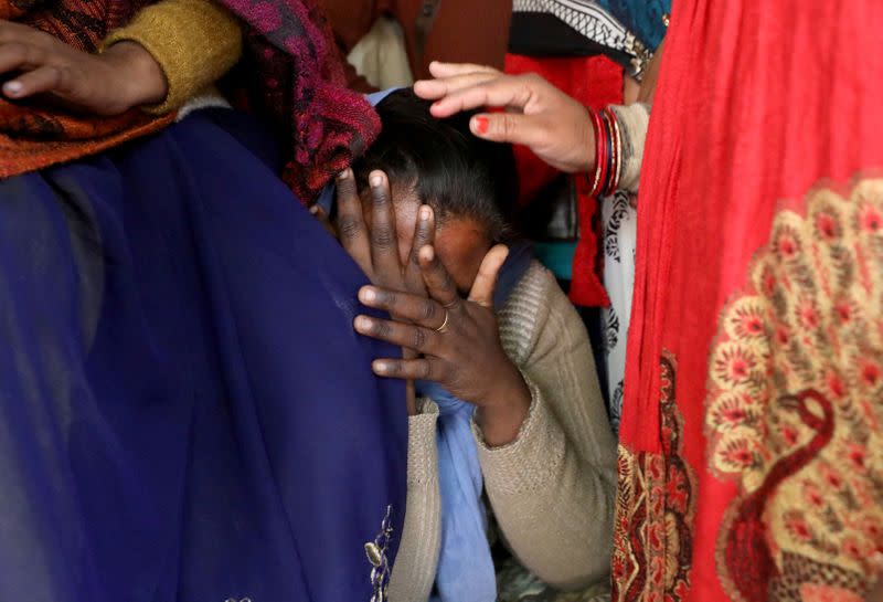 FILE PHOTO: A relative of a 23-year-old rape victim, who died in a New Delhi hospital on Friday after she was set on fire by a gang of men, which included her alleged rapists, is consoled as she mourns the death of the victim outside a house in Unnao