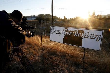 A TV cameraman films a sympathy sign at sunrise outside Umpqua Community College in Roseburg, Oregon, United States, October 2, 2015. REUTERS/Lucy Nicholson